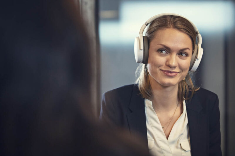 woman wearing over ear headset smiling and looking over slightly to her right