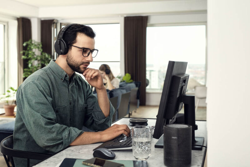 Man looking intently at computer while wearing a Skype headset