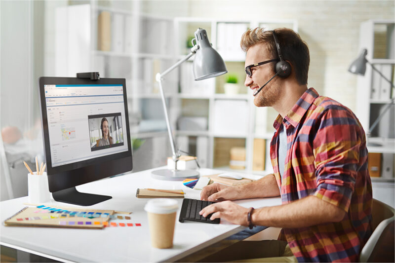 Man smiling at computer while wearing a Skype headset