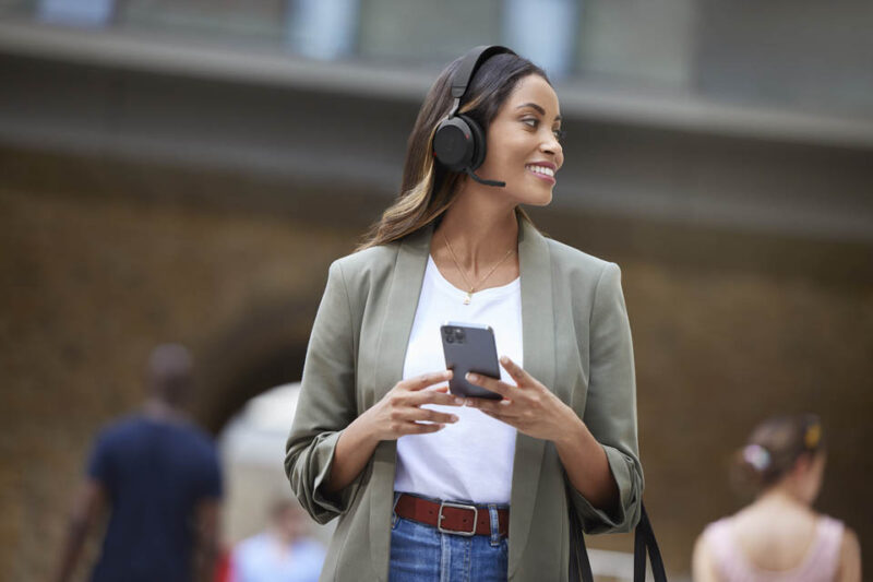 woman on street wearing stereo headset with mobile phone