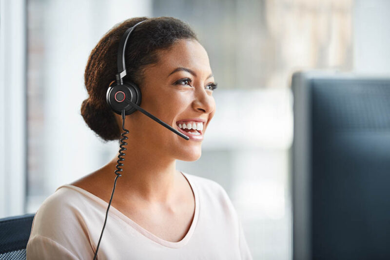 Image of smiling woman at desk wearing Google Meet headset