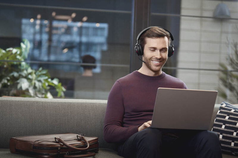 Image of man wearing noise cancelling headset while working on laptop