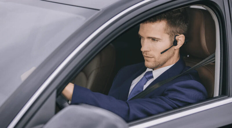 Image of man wearing Aftershokz bone conduction headset in car