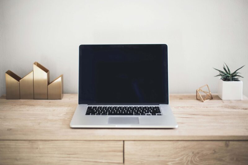 An open Macbook laptop sitting on a wooden desk